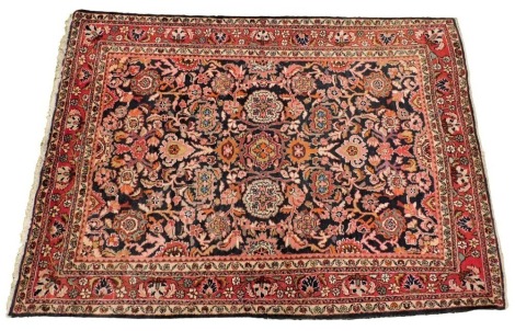 A Persian Tabriz black ground rug, the central field decorated with flowers and scrolling leaves, within repeating floral borders, 243cm x 163cm.