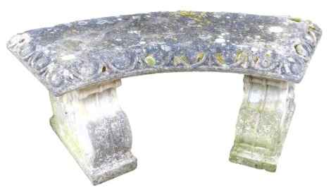 A reconstituted stone garden seat, of curved form raised on plinths, 107cm wide.