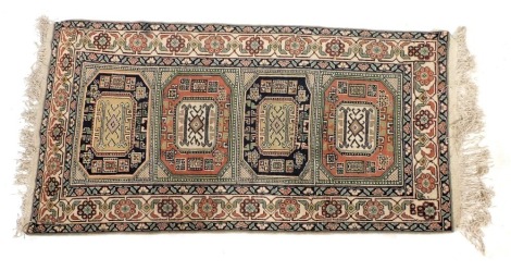 A Kazak cream ground rug, with four central medallions, within repeating floral borders, 203cm x 90cm.