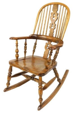 An oak and elm rocking chair, with a pierced vase shaped splat, solid saddle seat, raised on turned legs, 66cm wide.