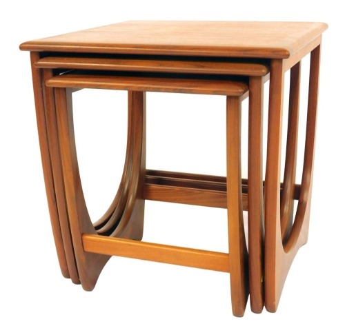 A nest of three G-Plan teak tables, each square top raised on a U shaped end support united by stretcher, the largest 51cm high, the top 50cm x 50cm.