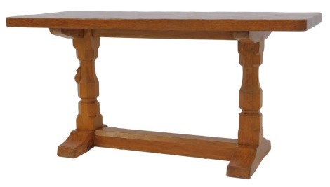 A Robert Mouseman Thompson of Kilburn oak coffee table, the rectangular top raised on two carved columns, one with mouse, on a trestle type base, 43cm high, the top 38cm x 91cm.