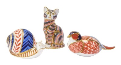 Three Royal Crown Derby porcelain paperweights, comprising a pheasant, 7cm high, a seated cat, 13cm high, and a snail, 7.5cm high, no stoppers.