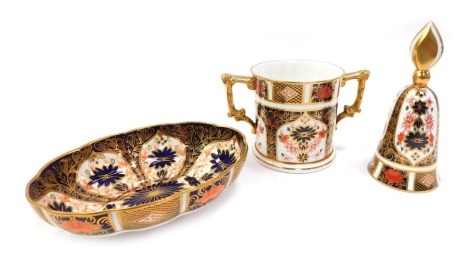 Three items of Royal Crown Derby porcelain decorated in the Old Imari pattern, comprising a loving cup, 7.5cm high, a handbell, 12.5cm high, and an oval trinket dish, 14.5cm wide.