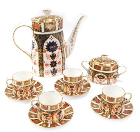 A Royal Crown Derby porcelain coffee service decorated in the Old Imari pattern, comprising a coffee pot, 22cm high, four coffee cups and saucers, and a twin handled sucrier, 1128, red printed marks.