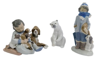 A group of Lladro porcelain figures, comprising boy seated beside dog and puppies, impressed number 5456, 12cm high, boy wearing coat beside a dog, 20cm high, and polar bear, 12cm high.