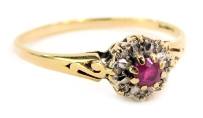 A 9ct gold dress ring, the ring head set with a central garnet, in a claw setting, surrounded by tiny diamonds illusion set, with scroll and pierced shoulders, ring size P½, 1.5g all in.