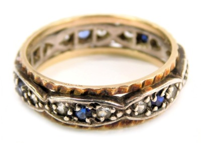 A wedding band, with a hammered gold coloured outer border, and white central oval panels each set with two white and one blue stone, yellow and white metal unmarked, ring size P½, 3.8g all in.