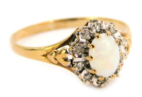 A 9ct gold dress ring, with a central oval opal, surrounded by tiny diamonds in a white gold setting, with V splayed shoulders on a yellow metal band, ring size O½, 1.9g all in.