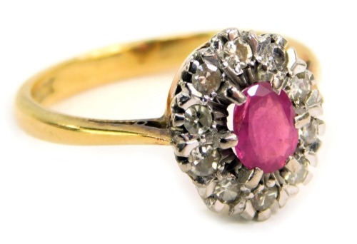 A ruby and diamond cluster ring, the central oval ruby in a six claw setting, approx 0.25ct, surrounded by ten round brilliant cut diamonds, each illusion set, approx 0.02ct, in platinum on a yellow metal band stamped 18ct, ring size P, 4.5g all in.