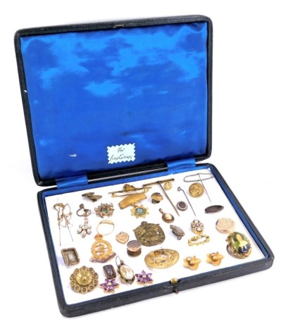 A presentation case containing stick pins and brooches, including Royal Army Medical Corps enamel badge, leaf moulded earrings, crescent brooch, seed pearl dress ring, stick pins, etc.