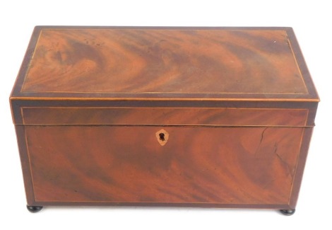 A George III rosewood and boxwood line inlaid tea caddy, of rectangular form with a lion mask and ring handle to each side, the hinged lid enclosing three recesses for tea, raised on compressed bun feet, 16cm high, 31cm wide, 15.5cm deep.