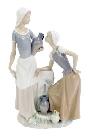 A Nao porcelain figure group, modelled as two female water carriers beside a pump, printed marks, 42cm high, boxed.