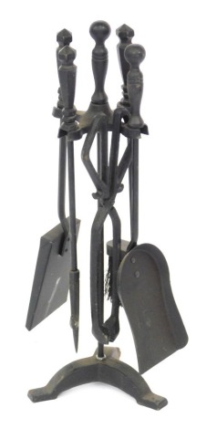 A 20thC cast fire side companion set, with tongs, two shovels, poker and brush, on a tripod base, 63cm high.