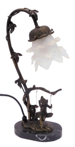 A table lamp, on a shaped oval marble foot, with an ebonised swing and child, with a floral glass shade, 38cm high. (AF)Buyer Note: WARNING! This lot contains untested or unsafe electrical items. It is supplied for scrap or reconditioning only. TRADE ONLY