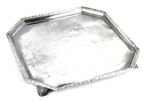 A George V silver salver, of square form with canted corners, the border with repeat triangle decoration, raised on four feet, London Britannia 1935, 21.42oz, 23.5cm wide.