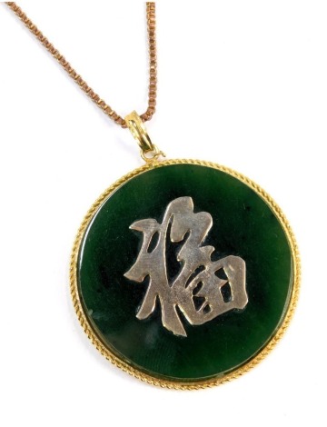 A Jadeite style Chinese necklace, the circular pendant with raised writing in a woven border, on fine link gold plated chain, the pendant 4cm wide.