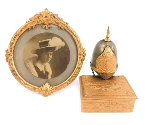 20thC gilded curios, comprising a miniature Royal Horseguards helmet, 10cm high, a trinket box with coach and horses, 3cm high, and a circular brass photograph frame, 13cm high. (3)