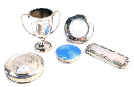 Five items of silver, comprising three silver dressing table jar lids, one with blue enamel set, a silver framed picture frame, and a silver winner's trophy cup, 3oz gross.