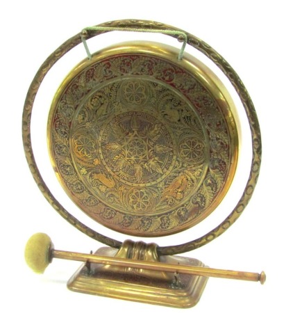 A Middle Eastern brass table gong, with engraved floral foliate panel and bird decoration, 32cm high, with a clanger.