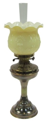 An early 20thC brass oil lamp, with a chimney and amber case glass frill shade moulded with stylised flowers, 59cm high.