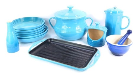 A group of turquoise Le Creuset wares, comprising two handled jar and cover, grill pan, salt dish, coffee can, bud vase, two large bowls, four medium bowls, and a dark blue pestle and mortar.