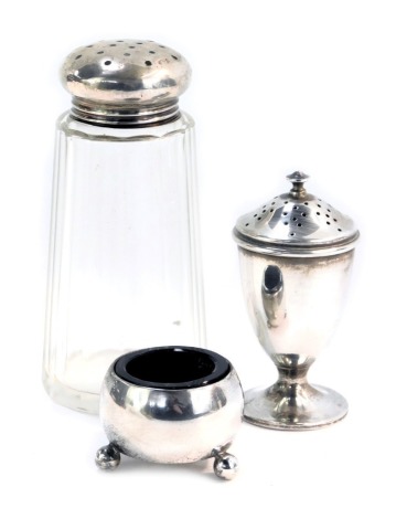 A George V silver pepper pot, Birmingham 1920, an Edward VII silver salt cellar, on three ball feet, Sheffield 1908, with blue glass liner, 1.69oz, and a silver topper sugar shaker. (3)