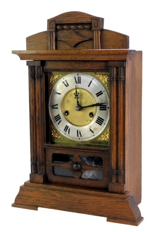 An early 20thC oak cased mantel clock, the carved cornice with a central crest and beaded decoration, on two columned supports, on a stepped base, with astragal glazed doors, on a brass square clock plate, with silvered dial, Roman numeric numerals and bl