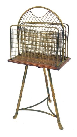 An early 20thC brass magazine rack, the pierced top on an oak base raised on cylindrical spiral turned legs united by stretchers, 78cm high.