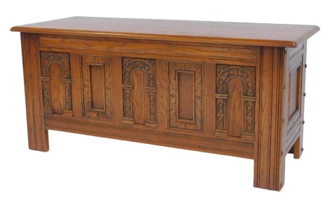 An Old Charm oak blanket chest, with carved front, on stiles, 52cm high, 114cm wide, 45cm deep.