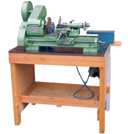 A Myford ML10 lathe, mounted to a pine bench, with extra chucks, etc.