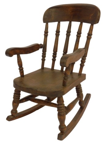 An elm child's rocking chair, with turned spindle back, solid seat and turned legs united by H-shaped stretcher, on rocker.