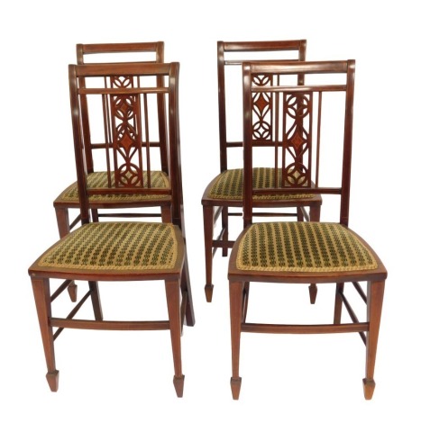 A set of four Edwardian mahogany and inlaid salon chairs, each with a pierced back, solid seat with overstuffed upholstery, on square tapering legs, with spade feet united by stretchers.