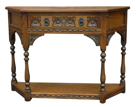 An Old Charm side table, the shaped top with carved frieze drawer and under tier united by turned columns, 76cm high, 102cm wide, 34cm deep.