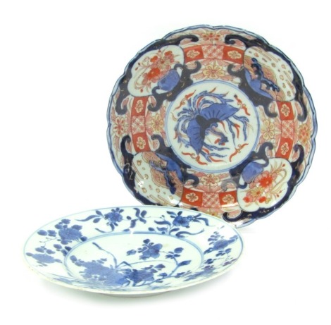 A 19thC Japanese plate decorated in the Imari pallet, 21.5cm diameter, together with a blue and white plate, decorated with flowers, 20.5cm diameter. (2)