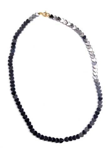 A heart shaped black necklace, with varying links, on a string strand with a yellow metal clasp and bolt, stamped 375, 42cm long, 21.7g all in.