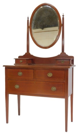 An Edwardian mahogany and line inlaid mirror back dressing table, the oval bevelled mirror supported by two square tapering plinths with turned finials, above two drawers, the base with two short and one long drawer, on square tapering legs, 172cm high, 9