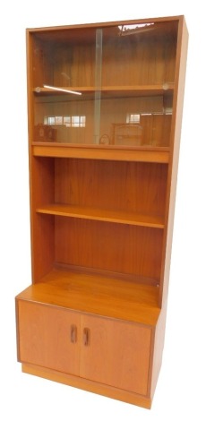 A G-Plan teak display cabinet, the top with two sliding doors enclosing shelf, with two further shelves, the base with two cupboards, on a plinth base, bearing label, 196cm high, 81cm wide, 48cm deep.