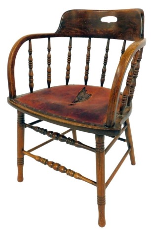 An early 20thC oak captain's type office chair, with spindle back, red leather overstuffed seat with stud work, on turned cylindrical legs united by stretchers.