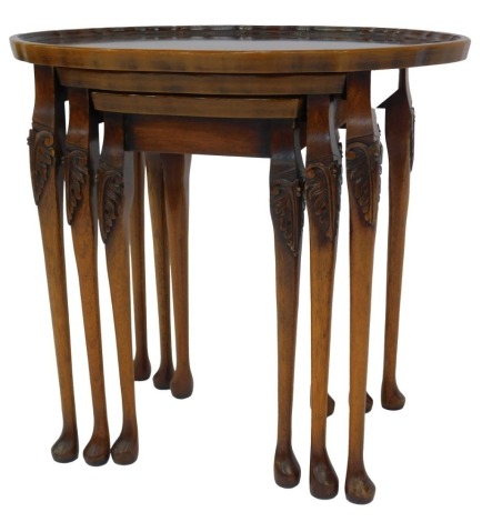 A Reprodux walnut nest of three tables, each with an oval galleried top, on scroll carved legs and pad feet, the largest 54cm high, 58cm wide.