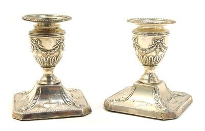 A pair of Victorian Adam style loaded silver dwarf candlesticks, embossed with urns, leaves and swags, Walter Latham, Sheffield 1899, 9.5cm high. Upon initial inspection the candlesticks are in a clean overall condition, both sconces are present and hallm