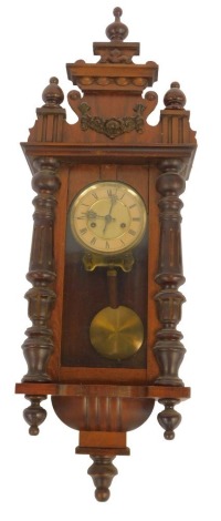 A Vienna walnut cased wall clock, with a stepped top with arched and raised floral finials, turned columns, with a Roman numeric face, 88cm high, 30cm wide, 14cm deep.