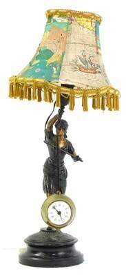 A 20thC spelter figural clock, modelled as a female warrior, possibly Joan of Arc, on an ebonised socle base, later converted to a table lamp, with shade, 61cm high overall. WARNING! This lot contains untested or unsafe electrical items. It is supplied fo