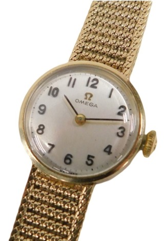 An Omega 9ct gold cased lady's wristwatch, with a small silvered circular numeric dial, on bark effect bracelet, the dial 2cm wide, 23.5g all in.