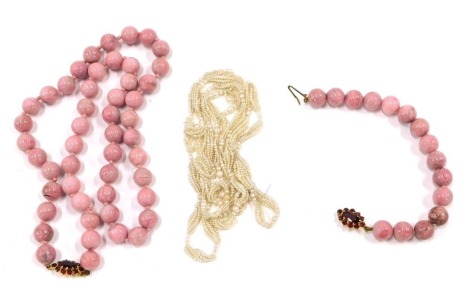 A pink marbled effect beaded necklace and bracelet set, with oval red garnet set clasps, yellow metal stamped 375, the necklace 60cm long, the bracelet 18cm long, and a group of seed pearls. (3)