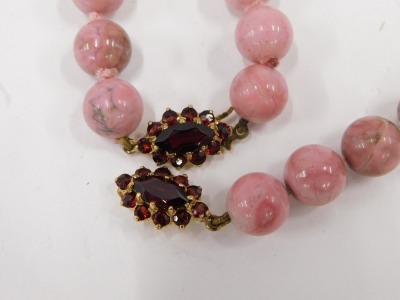 A pink marbled effect beaded necklace and bracelet set, with oval red garnet set clasps, yellow metal stamped 375, the necklace 60cm long, the bracelet 18cm long, and a group of seed pearls. (3) - 2