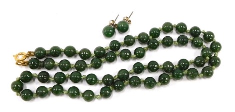 An imitation jade necklace and earring set, with oval beads, on a knotted green string stand with gold plated circular bolt ring clasp, 54cm long, and a pair of associated stud earrings, on white metal backs.