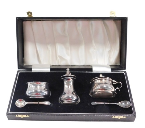 A silver three piece cruet set, of plain design comprising mustard, salt and pepper, each with blue glass liner, and two matched silver plated preserve spoons, the set Birmingham 1953, 3.29oz, in fitted case.