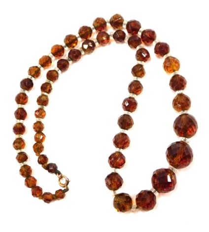 An amber style faceted necklace, with spherical beads and clear glass breaks, on knotted string strand, with yellow metal clasp stamped 375, 46cm long.