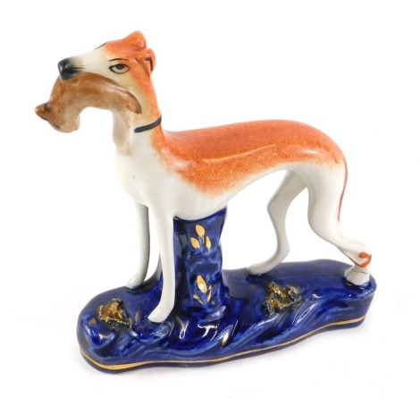 A late Staffordshire pottery model of a greyhound, holding a rabbit.